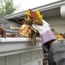 Person clearing leafs from gutters